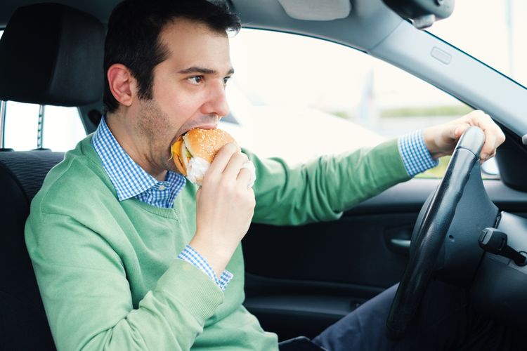 Nezdravé stravovacie návyky - muž konzumujúci hamburger v aute