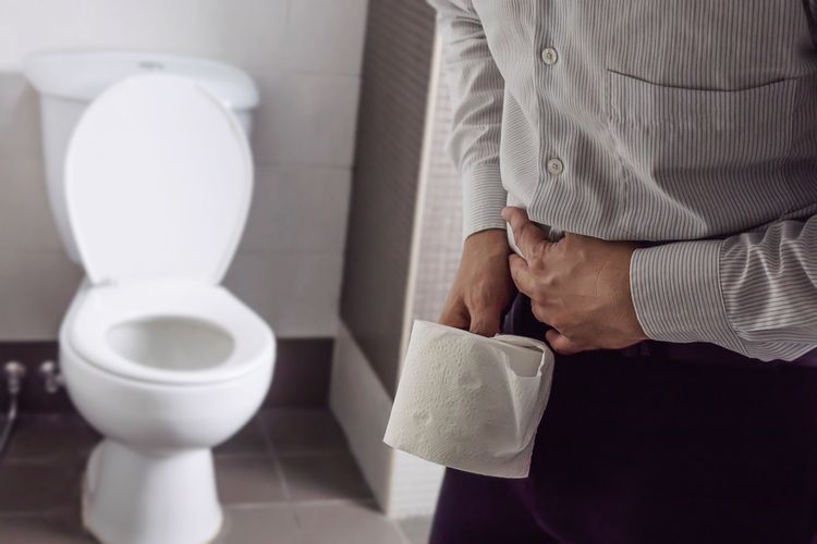 Problémy s hnačkou - muž s toaletným papierom pred toaletou